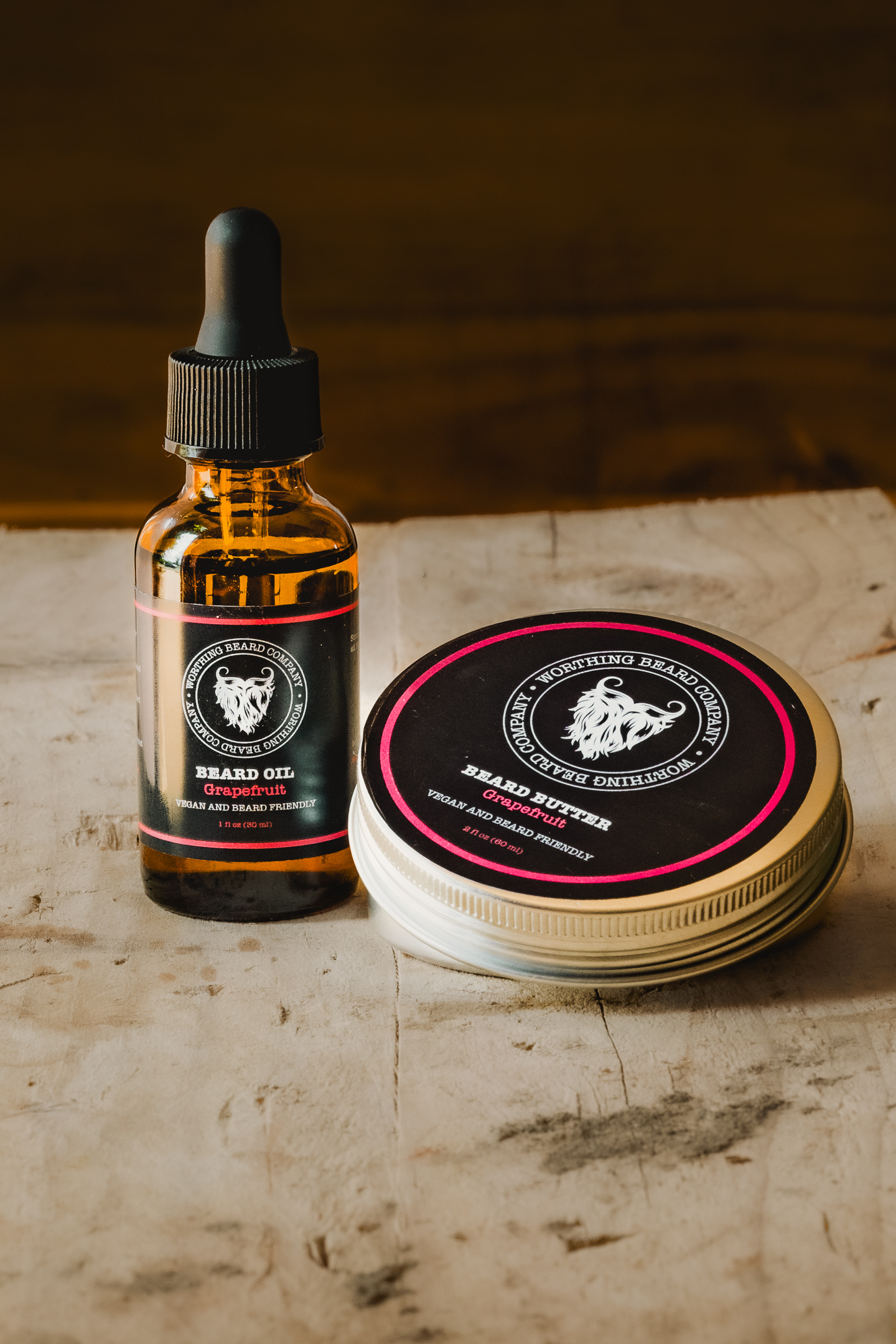 A bottle of beard oil with a dropper and a tin of beard balm gracefully rest on a wooden surface, captured beautifully by Hayley Kim Hall Photography.