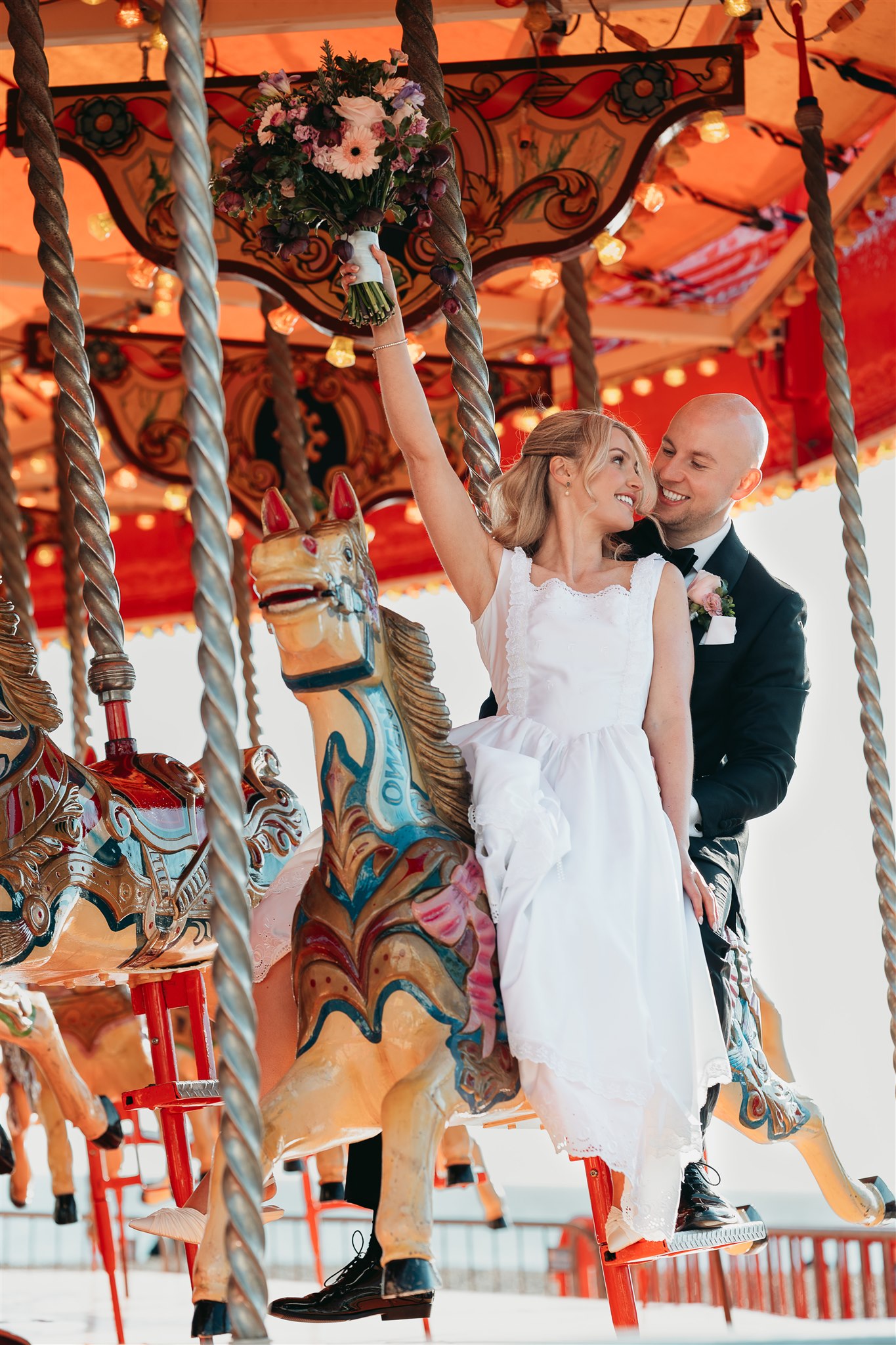 Bride and groom laughing together on a seafront carousel ride after their Regency Room wedding at Brighton Town Hall