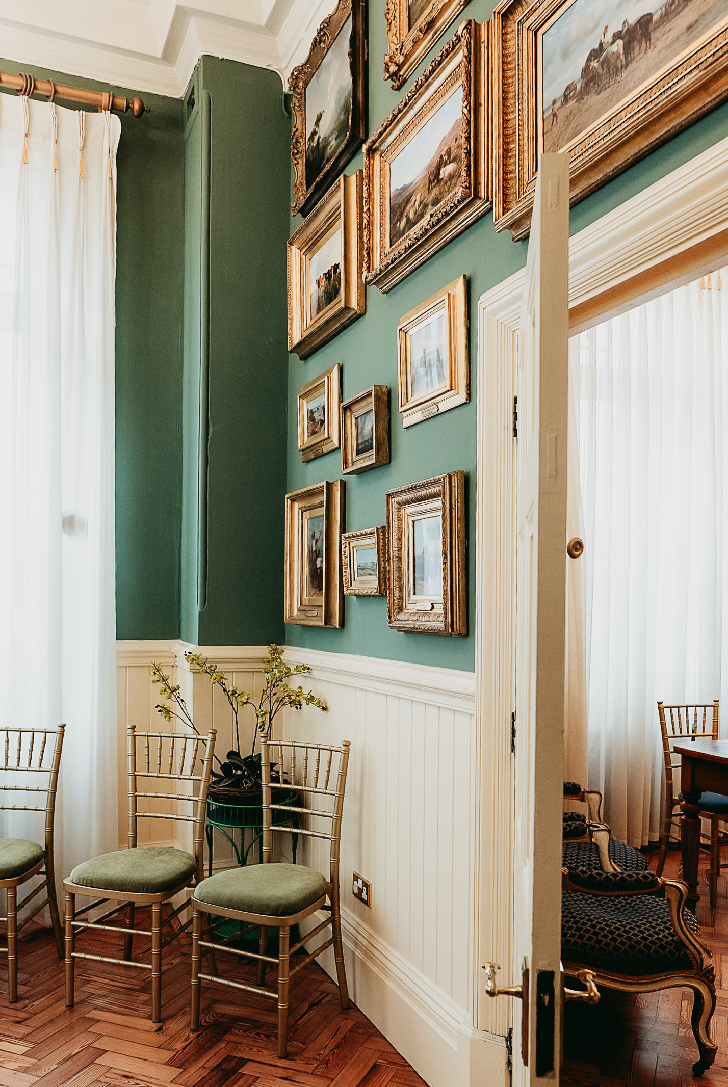 Green walls, framed paintings and antique furniture in the Fitzherbert Room at Brighton Town Hall