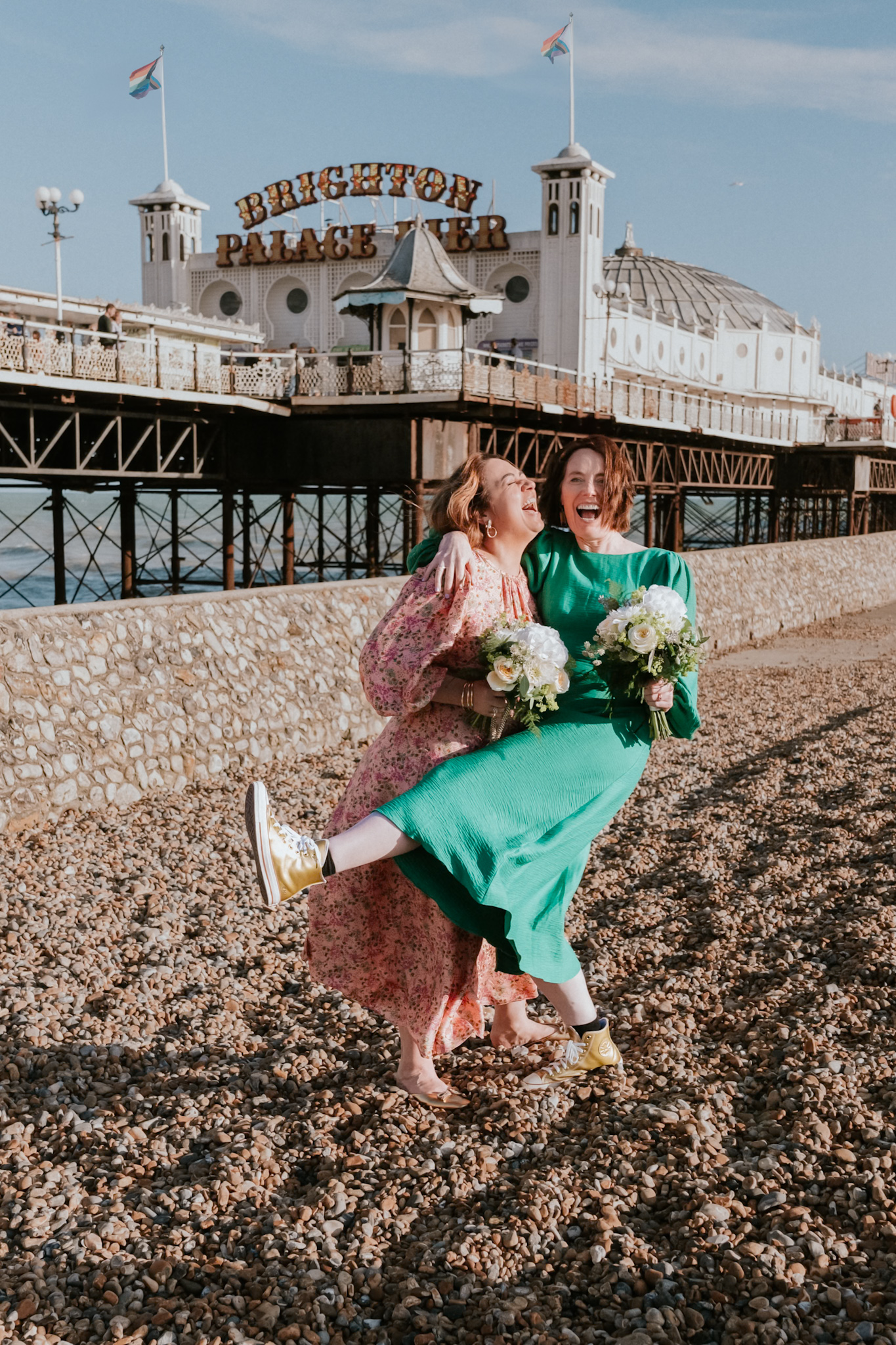 Bridesmaids in green and pink celebrating on Brighton Palace Pier after a Floral Room wedding at Brighton Town Hall