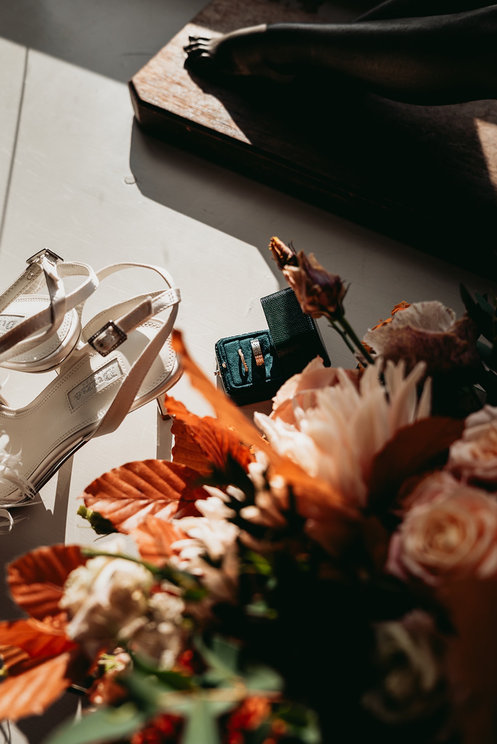 Wedding rings, pearl shoes and autumn flowers arranged together