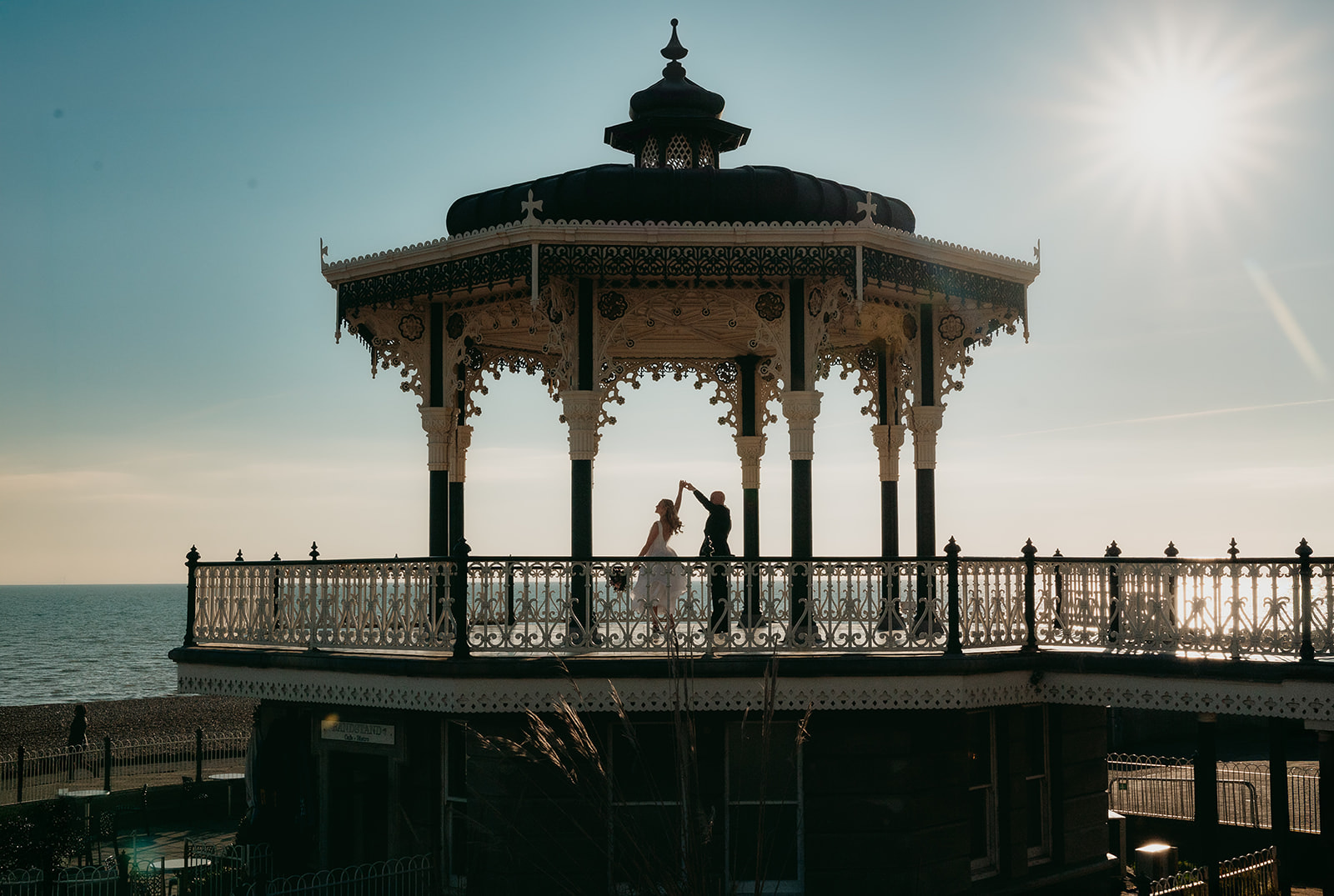 A newly married couple embracing at the Brighton bandstand after their Brighton Town Hall wedding
