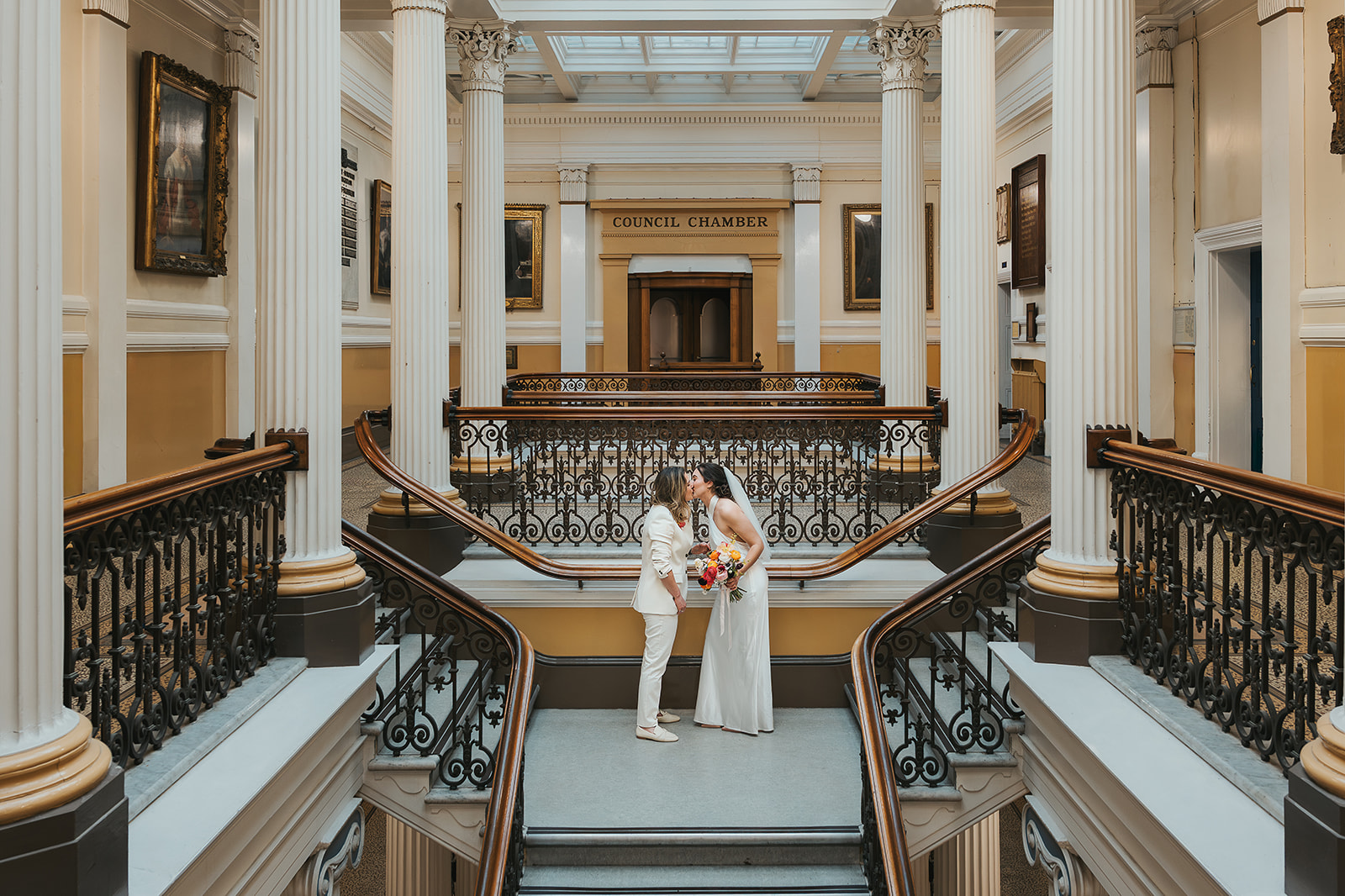 Two brides kissing on the historic staircase at Brighton Town Hall
