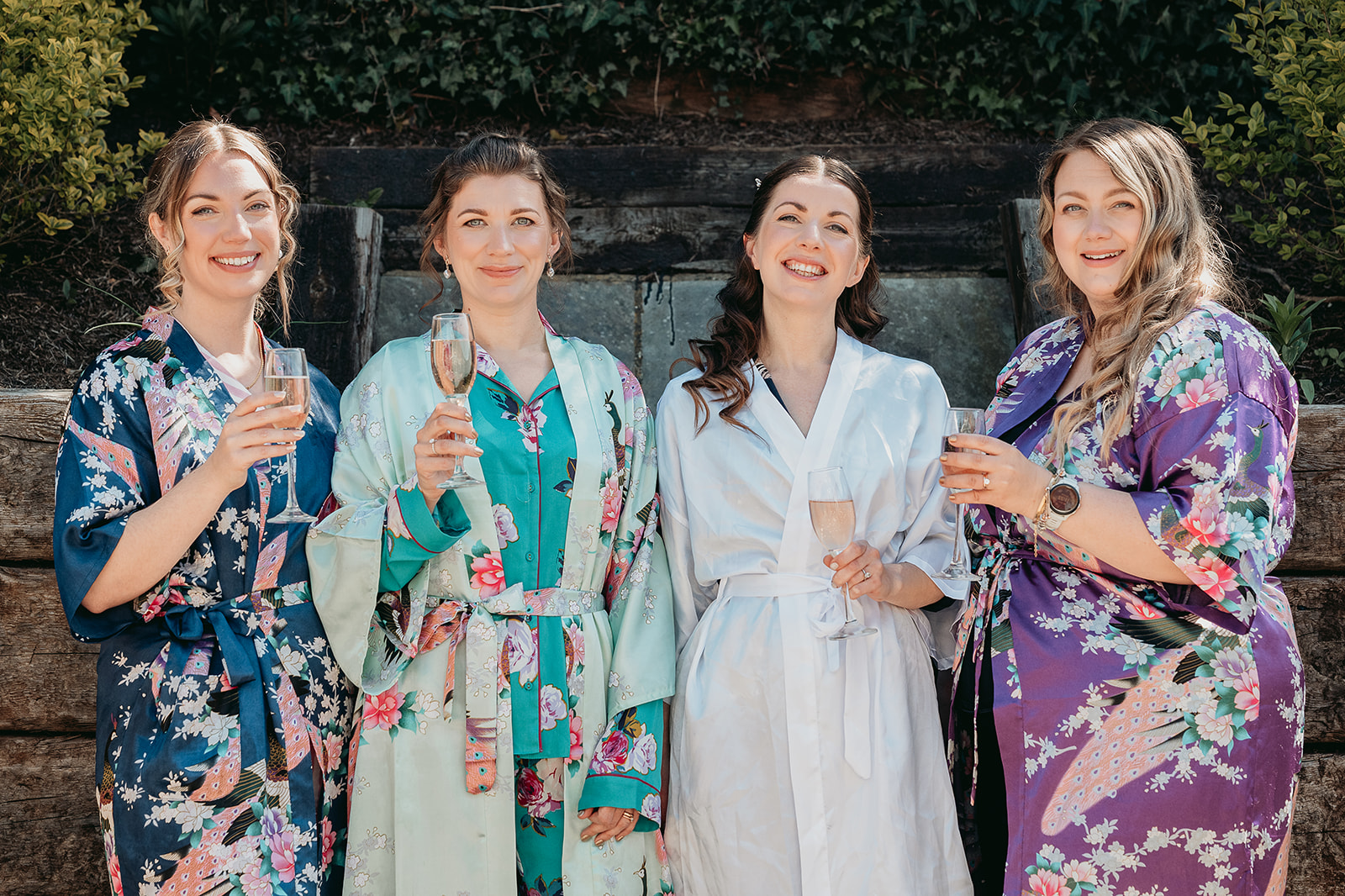 Bridesmaids in colourful dresses laughing together during wedding morning preparations