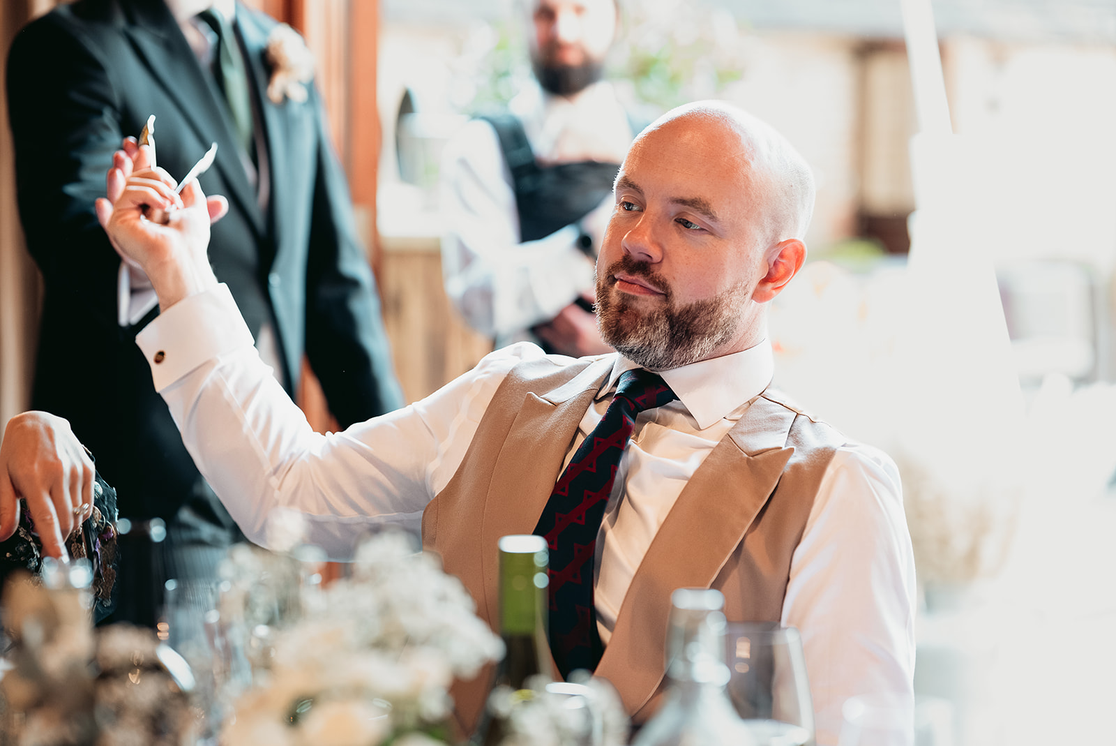 Wedding guests laughing during lively speeches inside Fitzleroi Barn