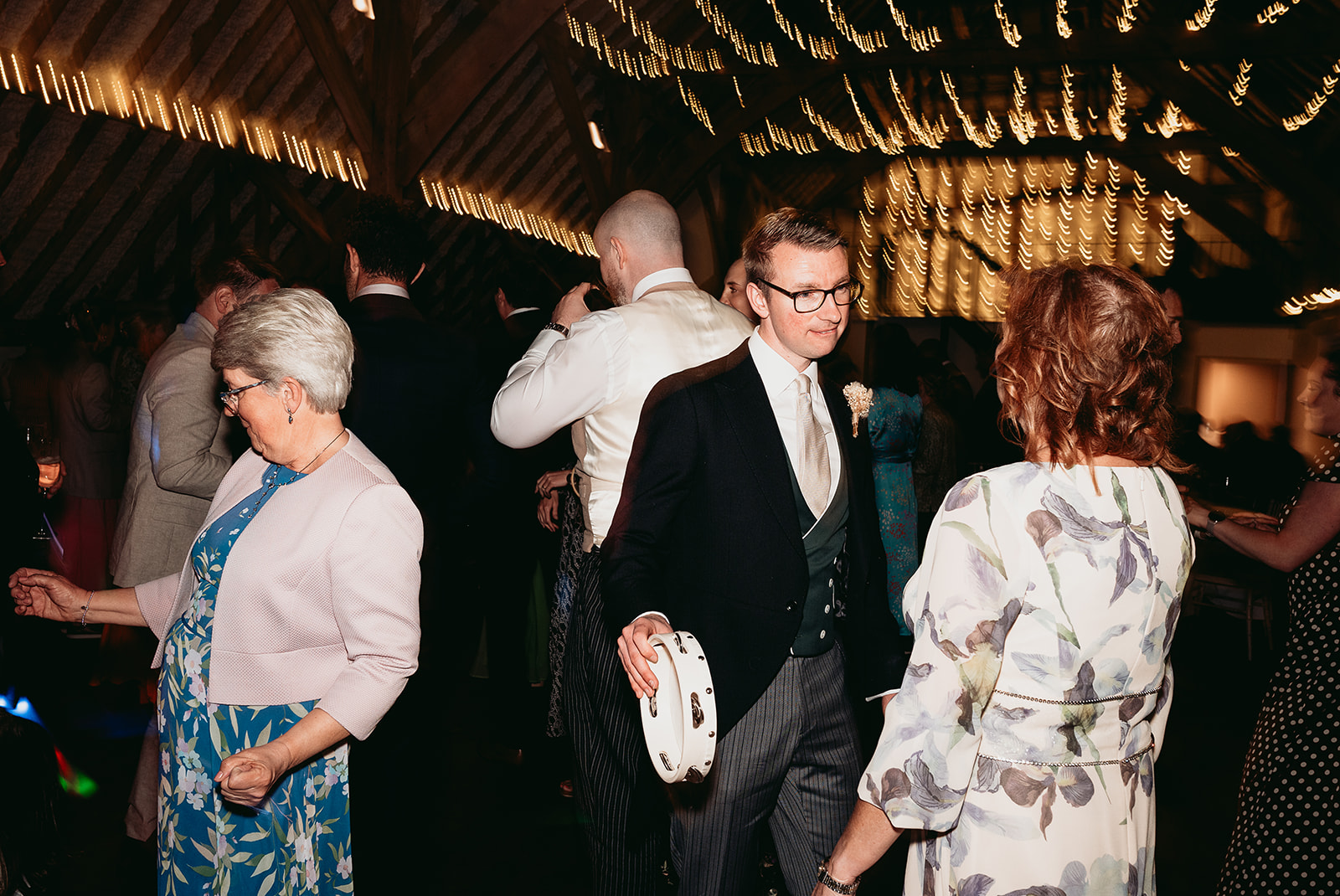 Friends celebrating beneath colourful party lights at Fitzleroi Barn