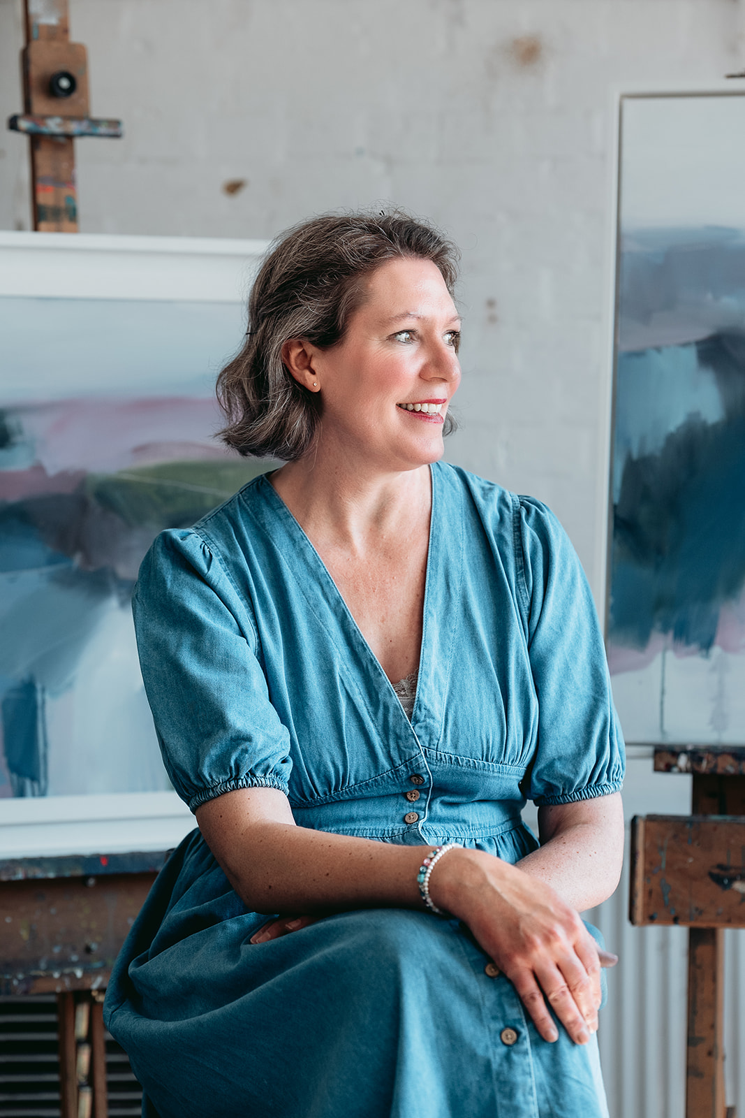 Sussex artist Lucy Beale seated among her paintings during a personal branding session