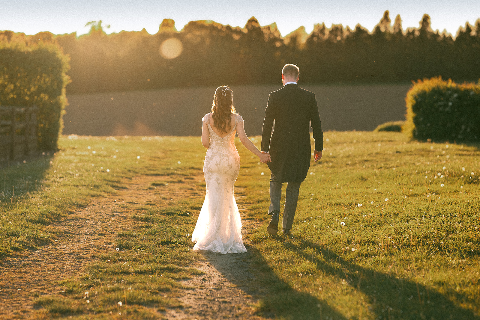 Jodie and Jordan walking through the Fitzleroi Barn meadow with South Downs countryside around them