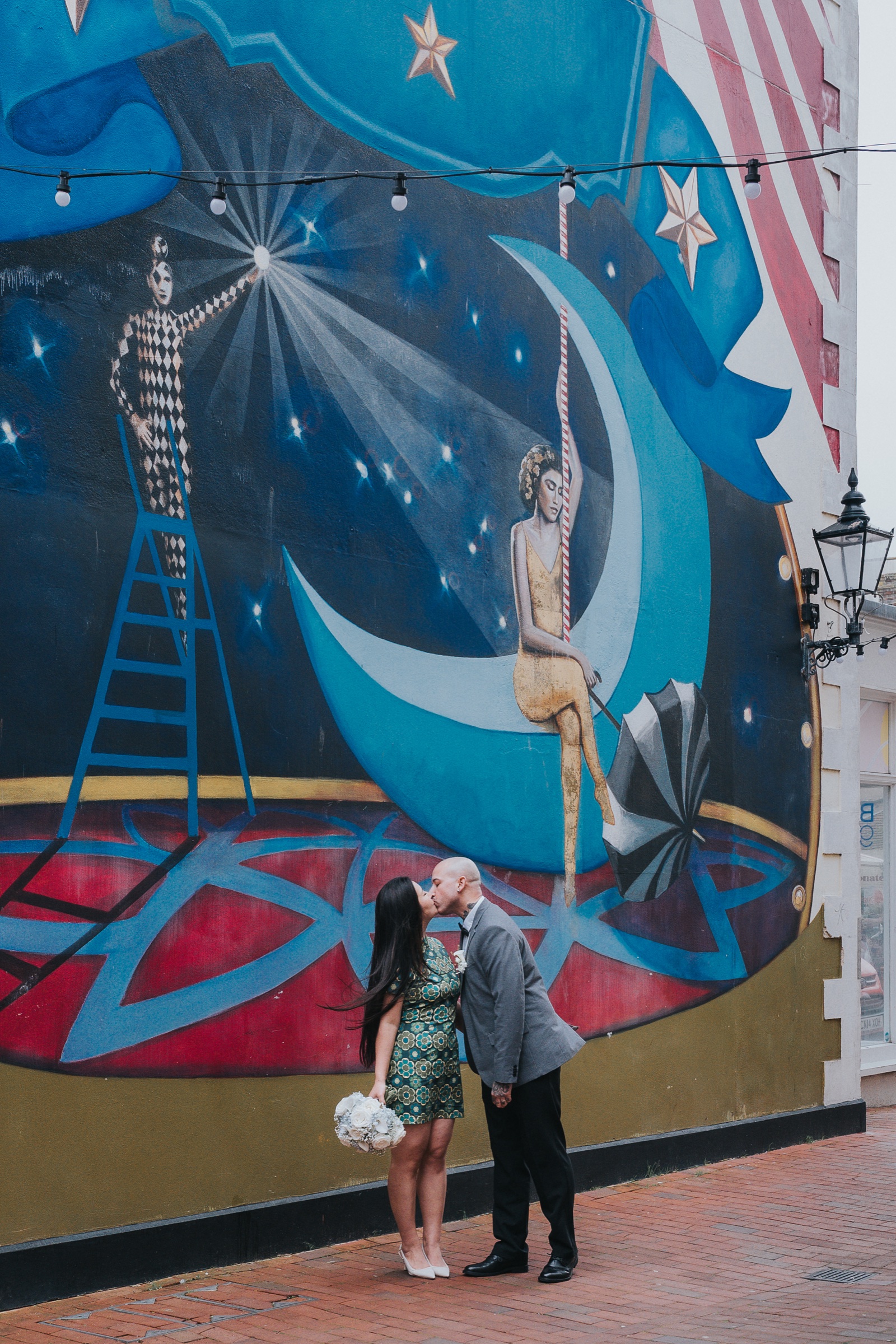 Newlyweds kissing beside a colourful mural in the Laines in Brighton